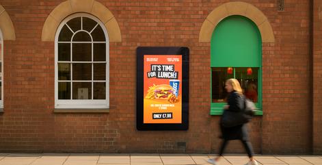 Digital display on a brick wall with a person walking by