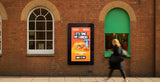 Digital display on a brick wall with a person walking by