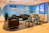 Modern office waiting area with blue walls, couches, chairs, and a digital display.