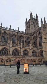 Large gothic cathedral with a person standing in front of it on a cloudy day.